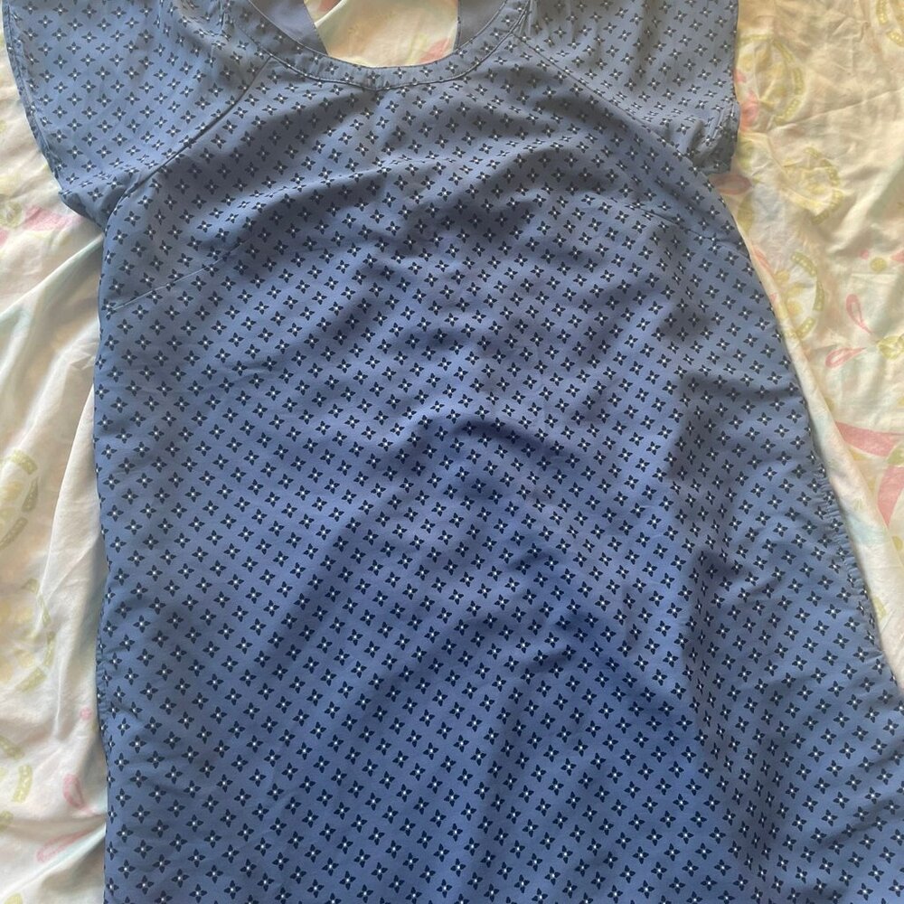 The garment in the image is a blouse or a short dress/tunic with a small geometr